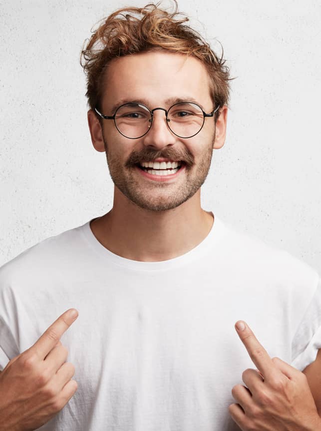 Mann som smiler og peker mot tennene